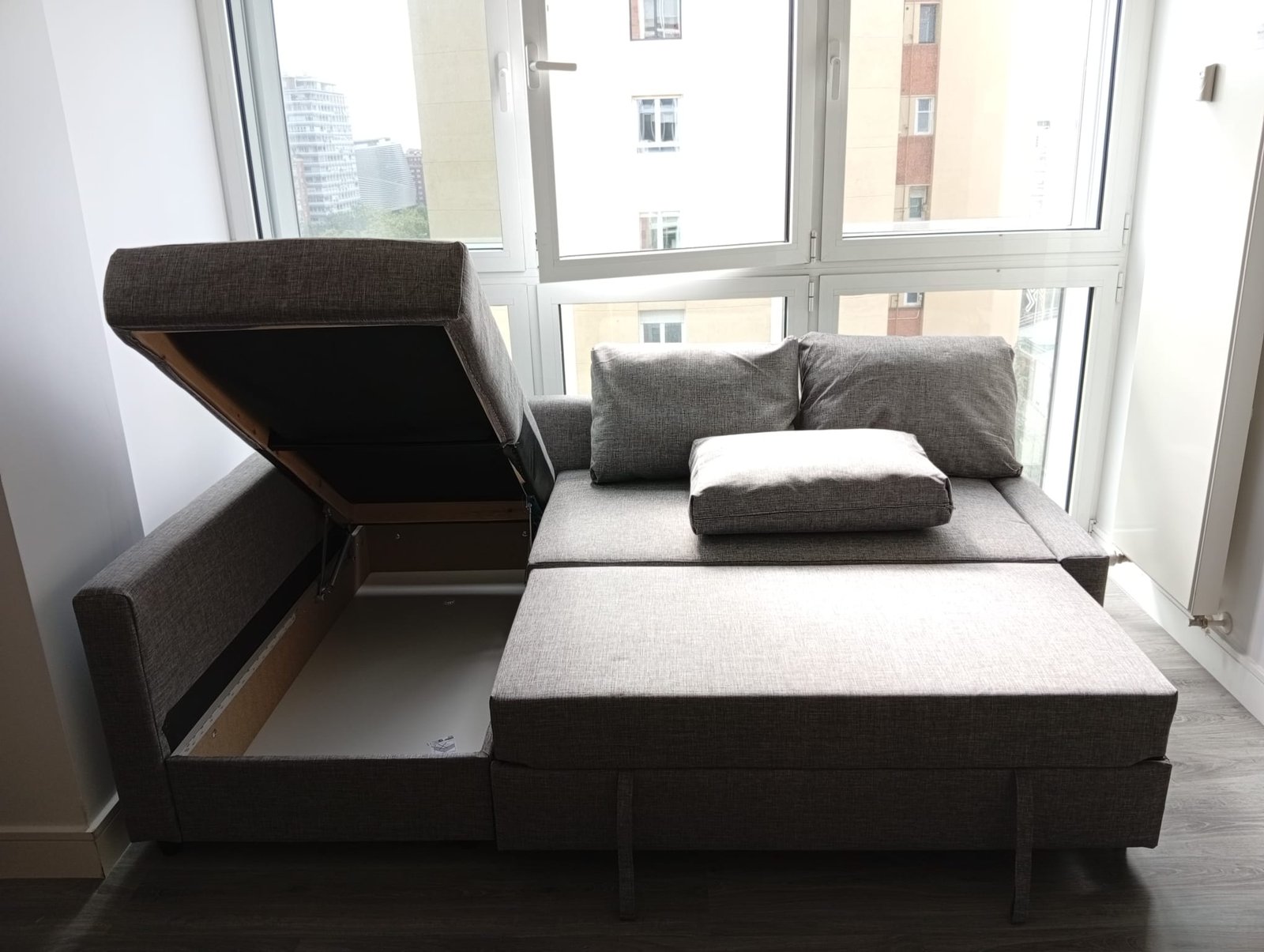 Sofá cama gris en sala iluminada